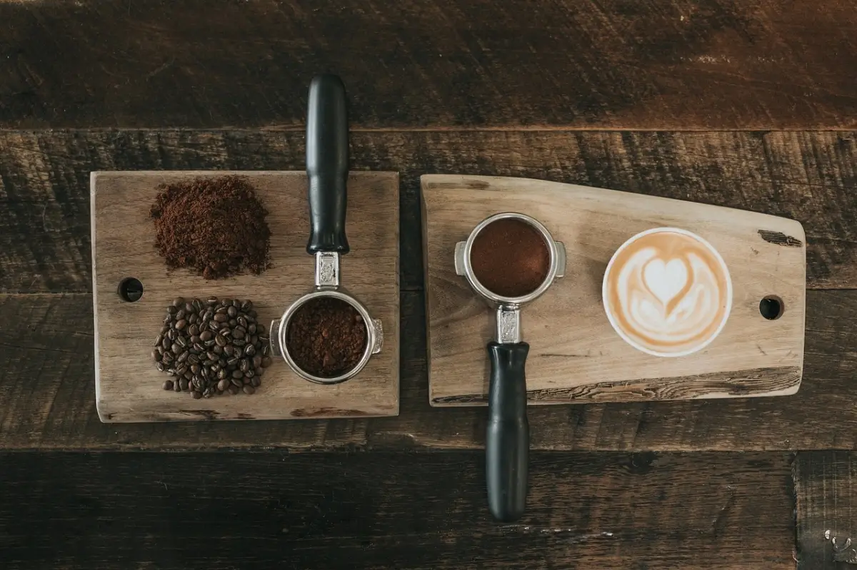 two wooden chopping boards on which there are coffee beans and ground coffee