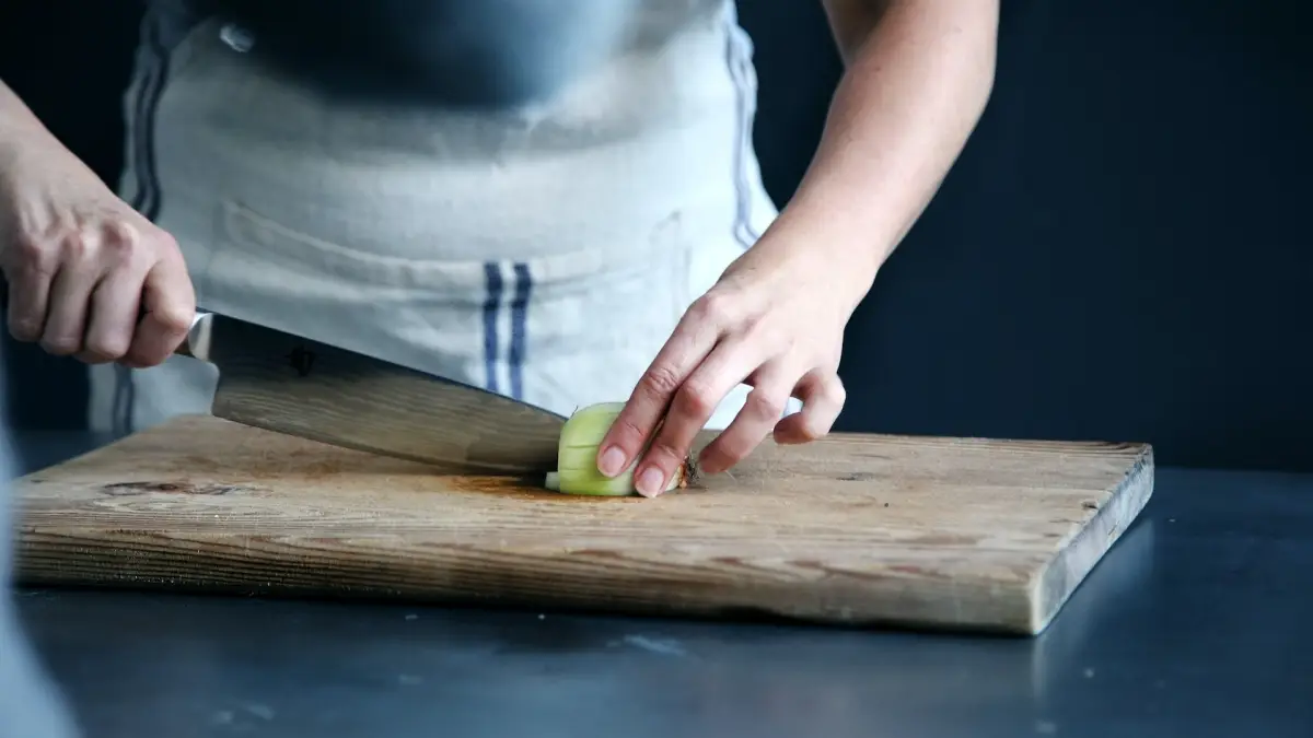 chef cuts onions on a wooden board